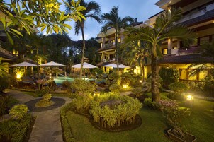 Un resort con piscina, mobiliario exterior y exuberante jardinería.