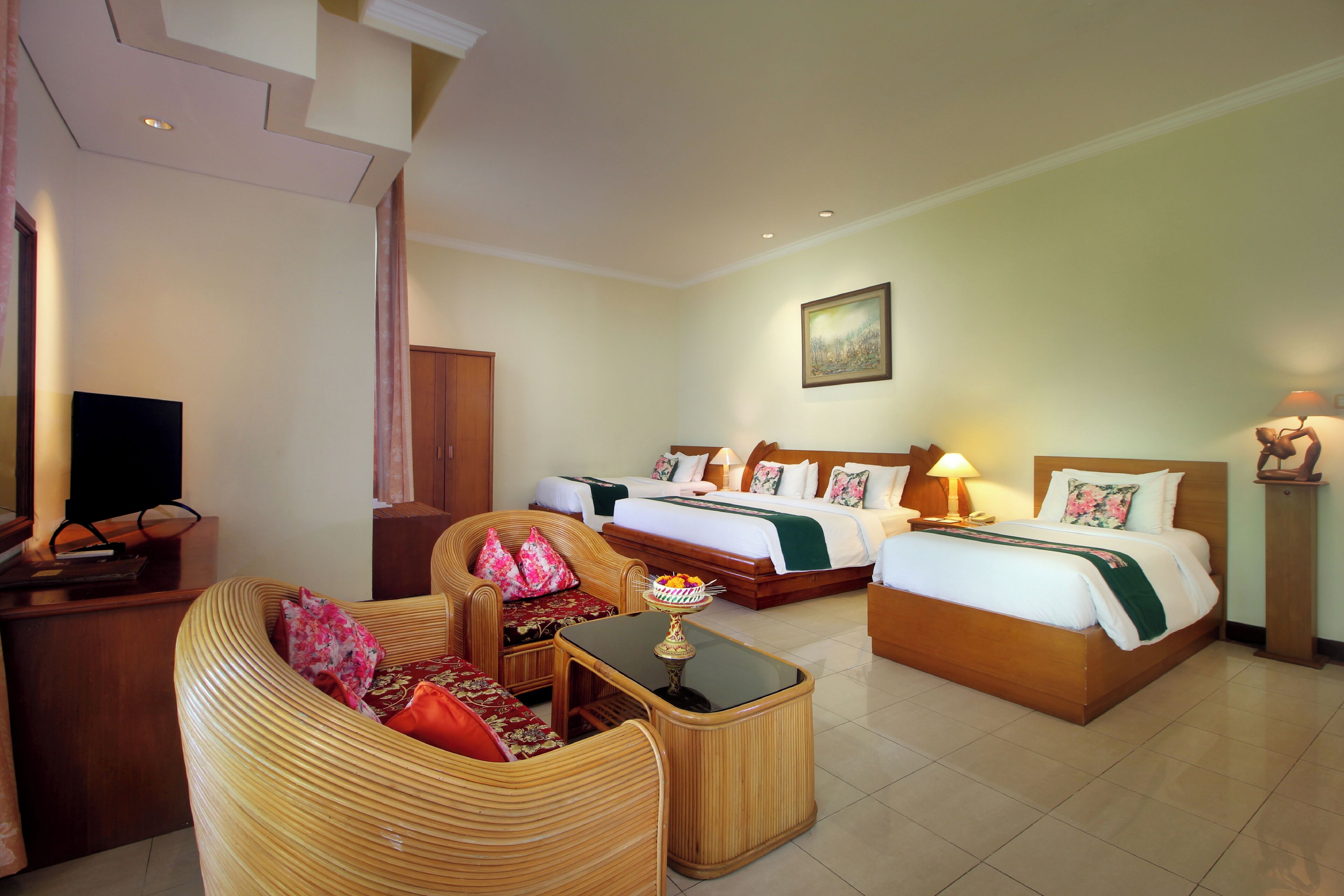 A hotel room with a bed, two sofas, a small table, and a television.