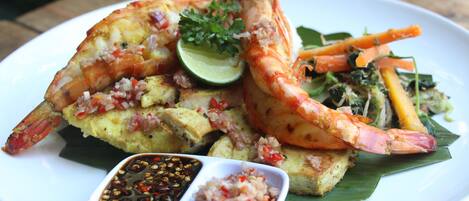 Un plato de comida con camarones, verduras y lima.