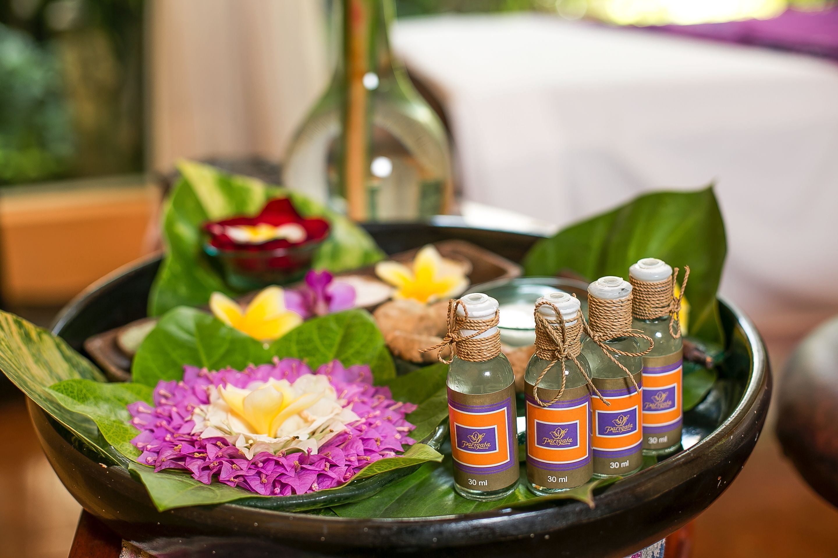 Una bandeja con botellas de aceites esenciales, flores y un frasco decorativo.