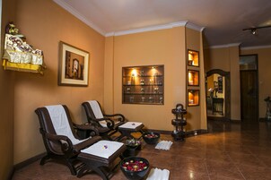 Ein Spa-Raum mit zwei Massagesesseln, einem Regal mit Flaschen und einem gerahmten Bild an der Wand.
