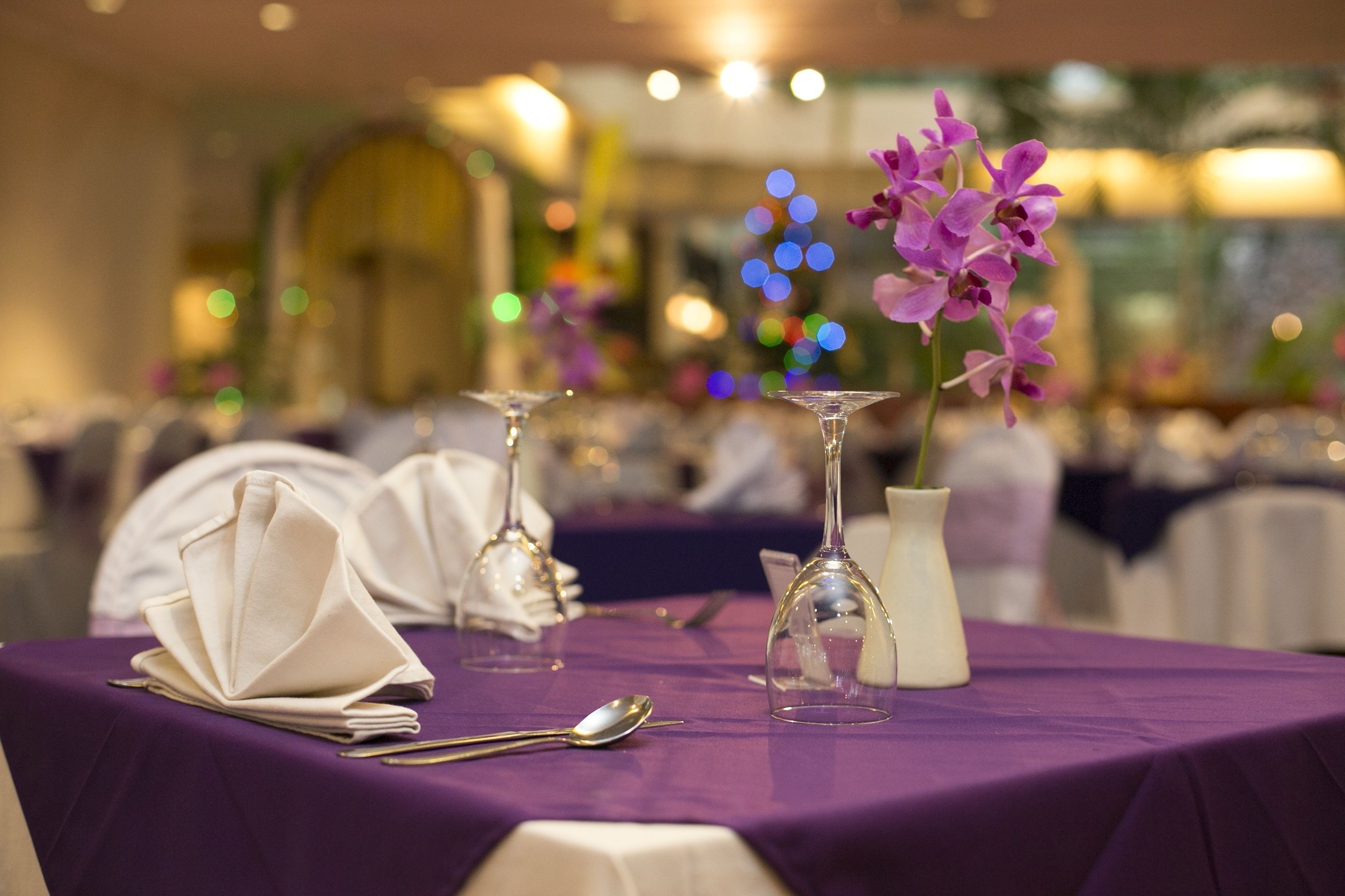 A table set with a purple tablecloth, white napkins, and clear glassware.
