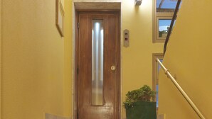 A staircase with marble steps and red carpet, leading to a wooden door with a glass panel. - Hotel Arco Romana (Milan)