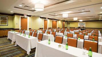 Un salón de conferencias con varias mesas y sillas dispuestas en filas.