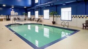 Una piscina interior con agua cristalina, rodeada por un suelo y paredes de azulejos, con un reloj y señalización informativa en las paredes.