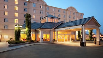 Un hotel con entrada cubierta, ventanas amplias y fachada bien iluminada.