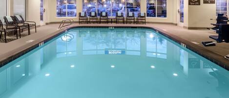 A large indoor swimming pool with clear water, surrounded by lounge chairs and a spa lift area.
