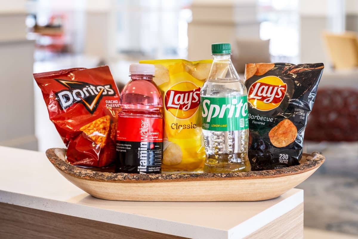 A wooden bowl containing snacks and drinks on a counter.