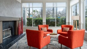 A spacious living area with large windows, a fireplace, and two orange armchairs.