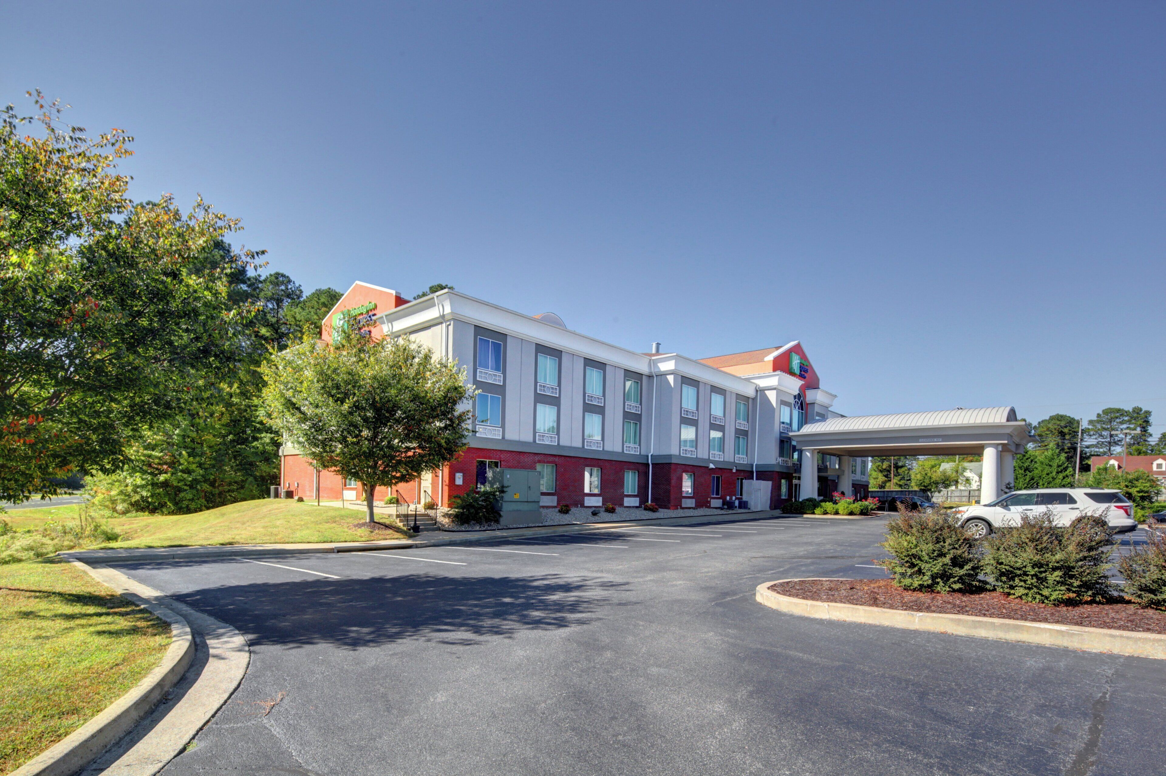 A multi-story hotel with a parking lot and a gas station.