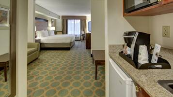 A hotel room with a bed, a desk, a microwave, and a coffee maker.