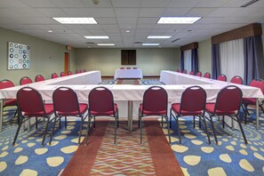 A conference room with a long table, red chairs, patterned carpet, and a ceiling with fluorescent lights. - Holiday Inn Express Hotel & Suites Emporia by IHG (Emporia)