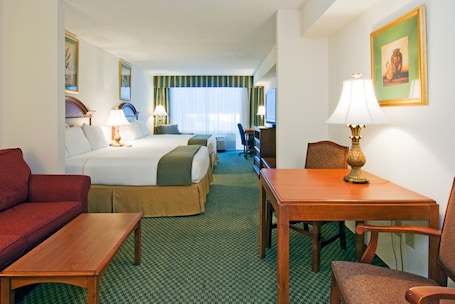 A hotel room with a bed, a desk, a chair, a sofa, and a television.