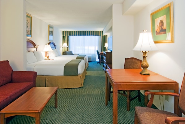 Ein Hotelzimmer mit einem Bett, einem Schreibtisch, einem Sessel, einer Couch und einem Fernseher.