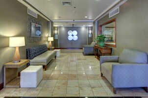 A hotel lobby with a reception desk, seating area, and a decorative wall with a circular light fixture.