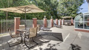 An outdoor patio with a table and chairs, a covered seating area, and a glass enclosure. - Holiday Inn Express Hotel & Suites Emporia by IHG (Emporia)