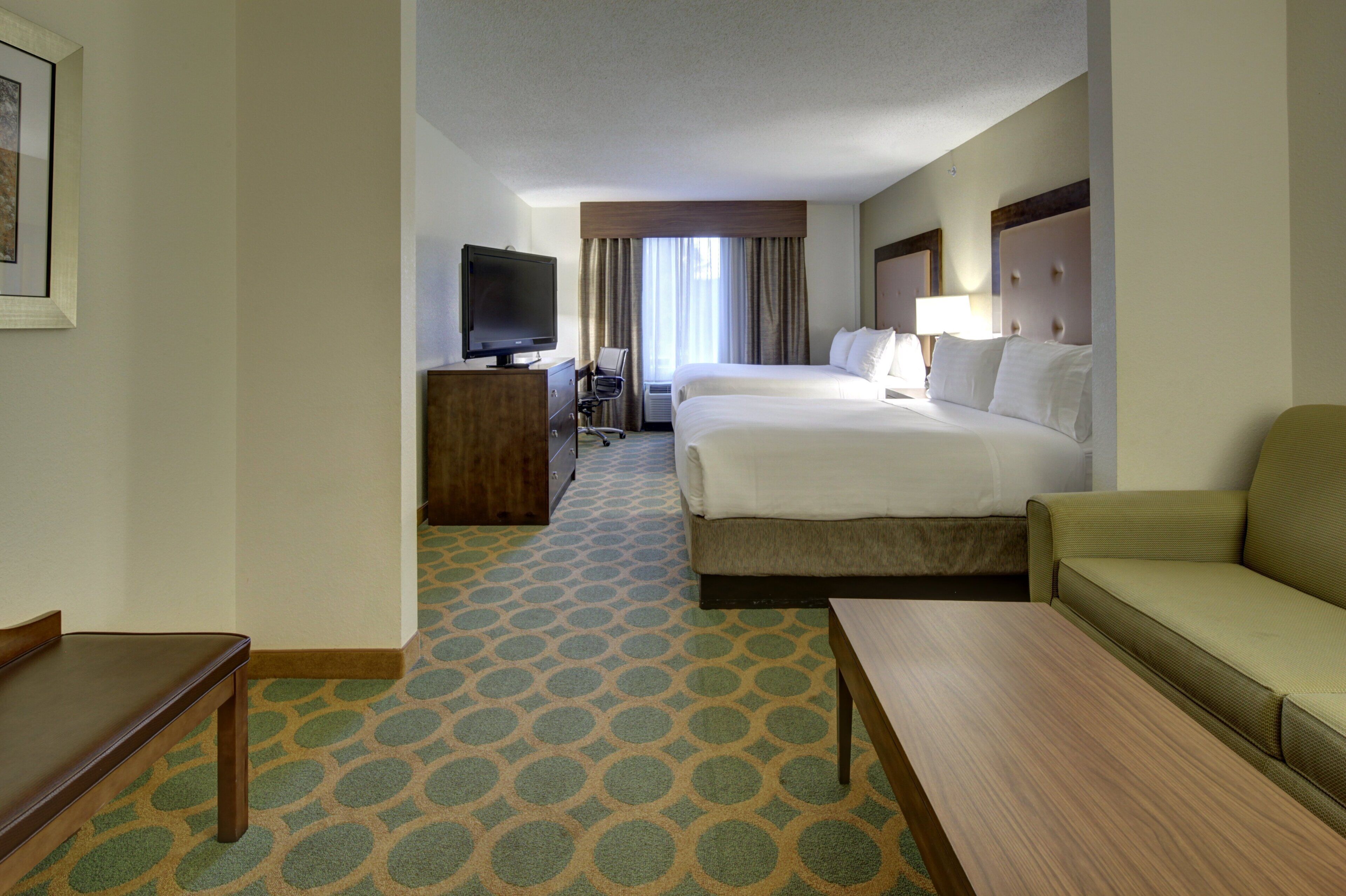 Een hotelkamer met een bed, een bureau, een televisie en een bank.