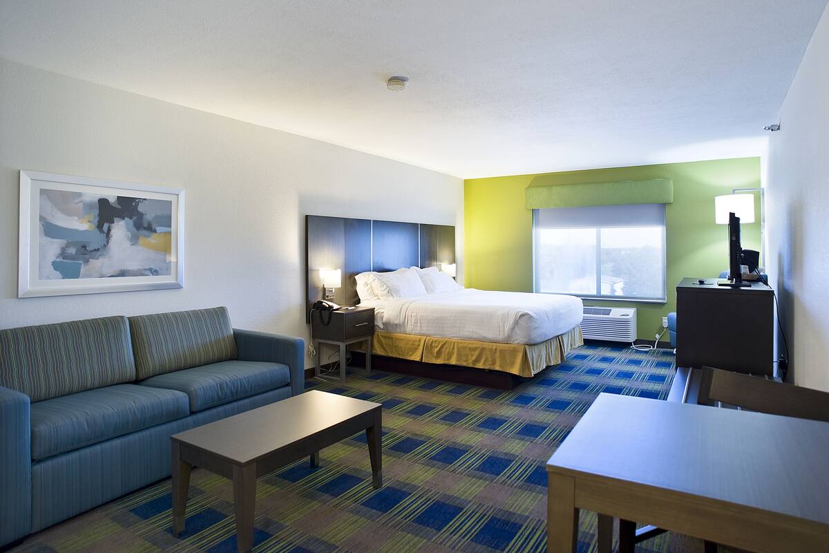 A hotel room with a bed, a sofa, a desk, and a table.