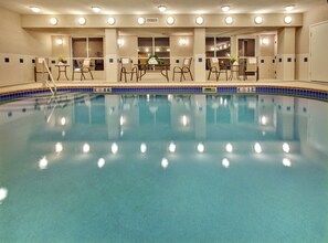 A swimming pool with a tiled edge, surrounded by chairs and tables, and a ceiling with recessed lighting. - Holiday Inn Express Hotel & Suites Vermillion by IHG (Vermillion)