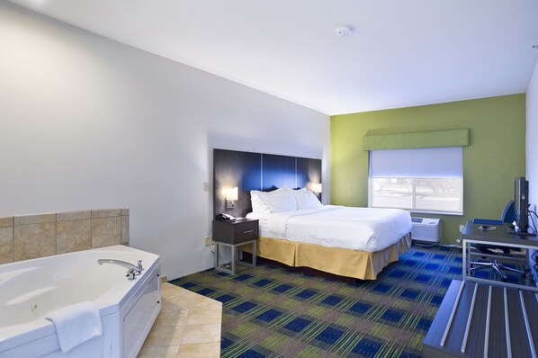 A hotel room with a large bed, a separate bathroom with a bathtub, a desk with a chair, and a window with blinds. - Holiday Inn Express Hotel & Suites Vermillion by IHG (Vermillion)