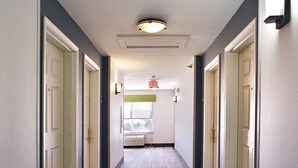 A hotel hallway with carpeted floors, white doors, and a ceiling light fixture. - Holiday Inn Express Hotel & Suites Vermillion by IHG (Vermillion)
