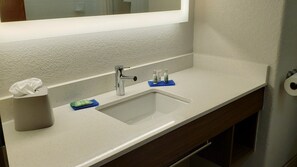 A bathroom sink with a mirror, a tissue roll, and two soap dispensers on a white countertop. - Holiday Inn Express Hotel & Suites Weslaco by IHG (Weslaco)
