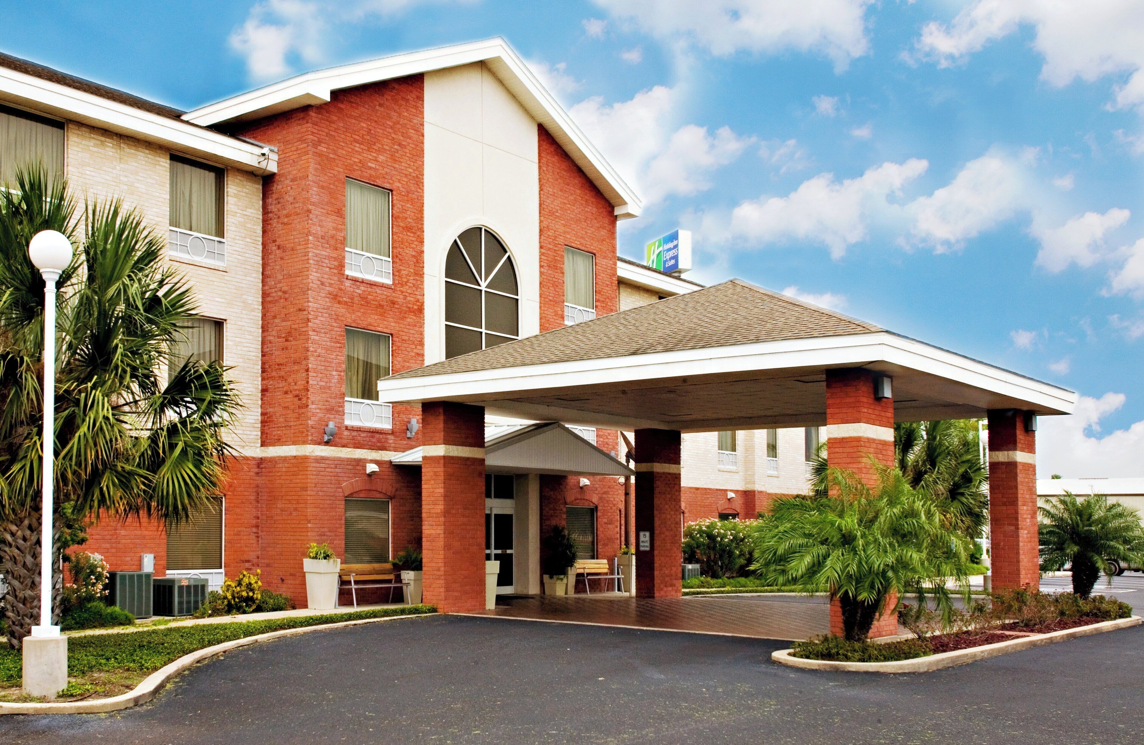 A hotel with a covered entrance, brick facade, and a sign for a nearby Express Lanes.
