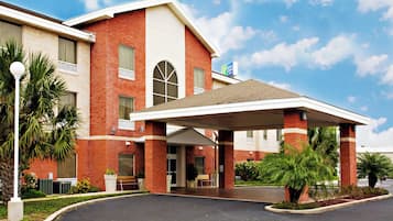 A hotel with a covered entrance, brick facade, and a sign for a nearby Express Lanes.