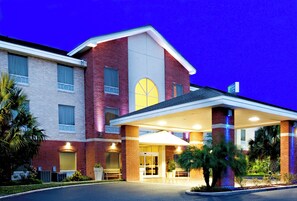 A hotel with a brick facade, a large entrance canopy, and a clock above the main door. - Holiday Inn Express Hotel & Suites Weslaco by IHG (Weslaco)