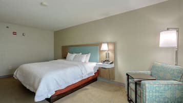 Una habitación de hotel con cama, mesita de noche, lámpara y silla.