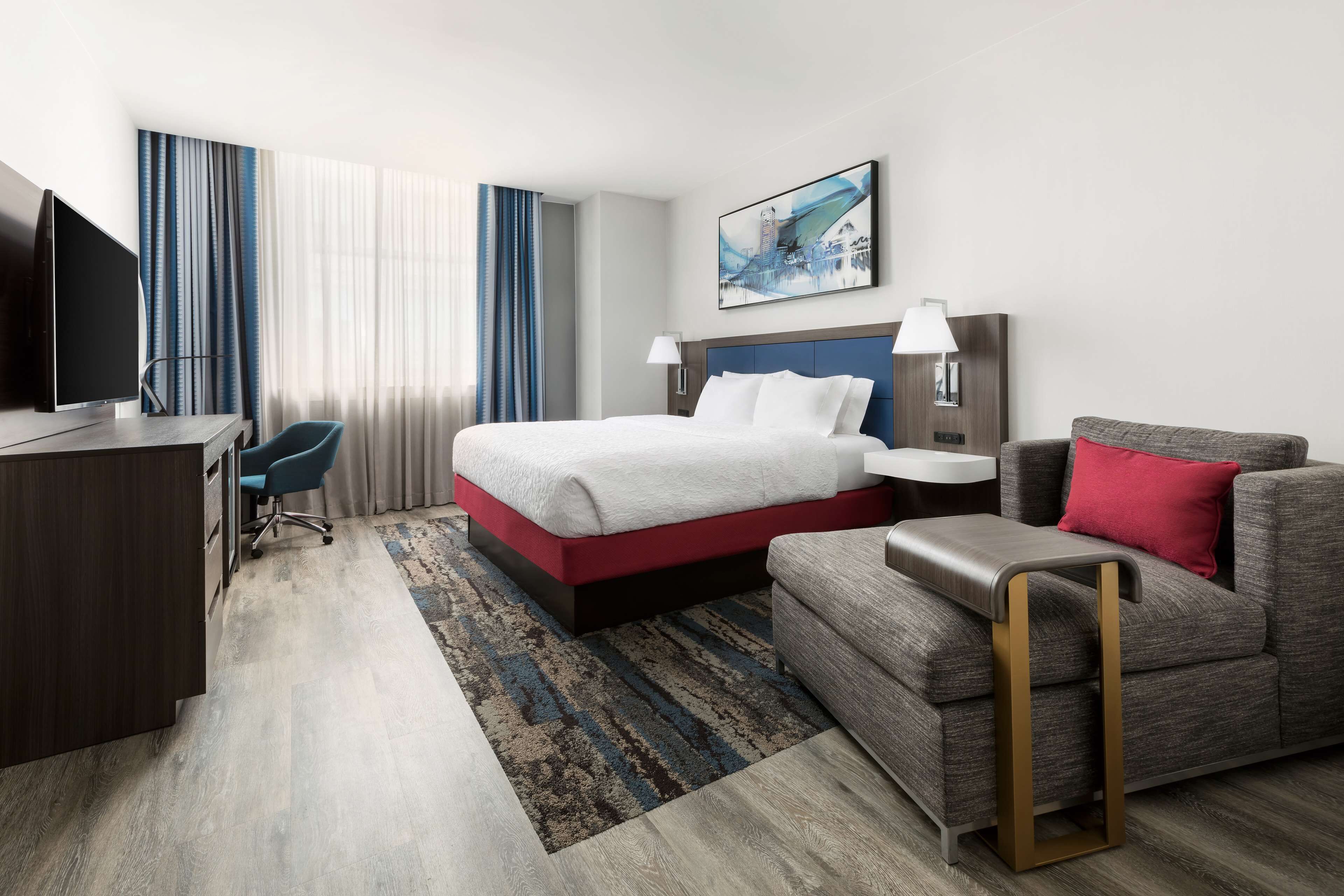Una habitación de hotel con cama, escritorio, silla, sofá y televisión.