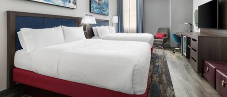 A hotel room with a large bed, a desk, a chair, a TV, and artwork on the walls.