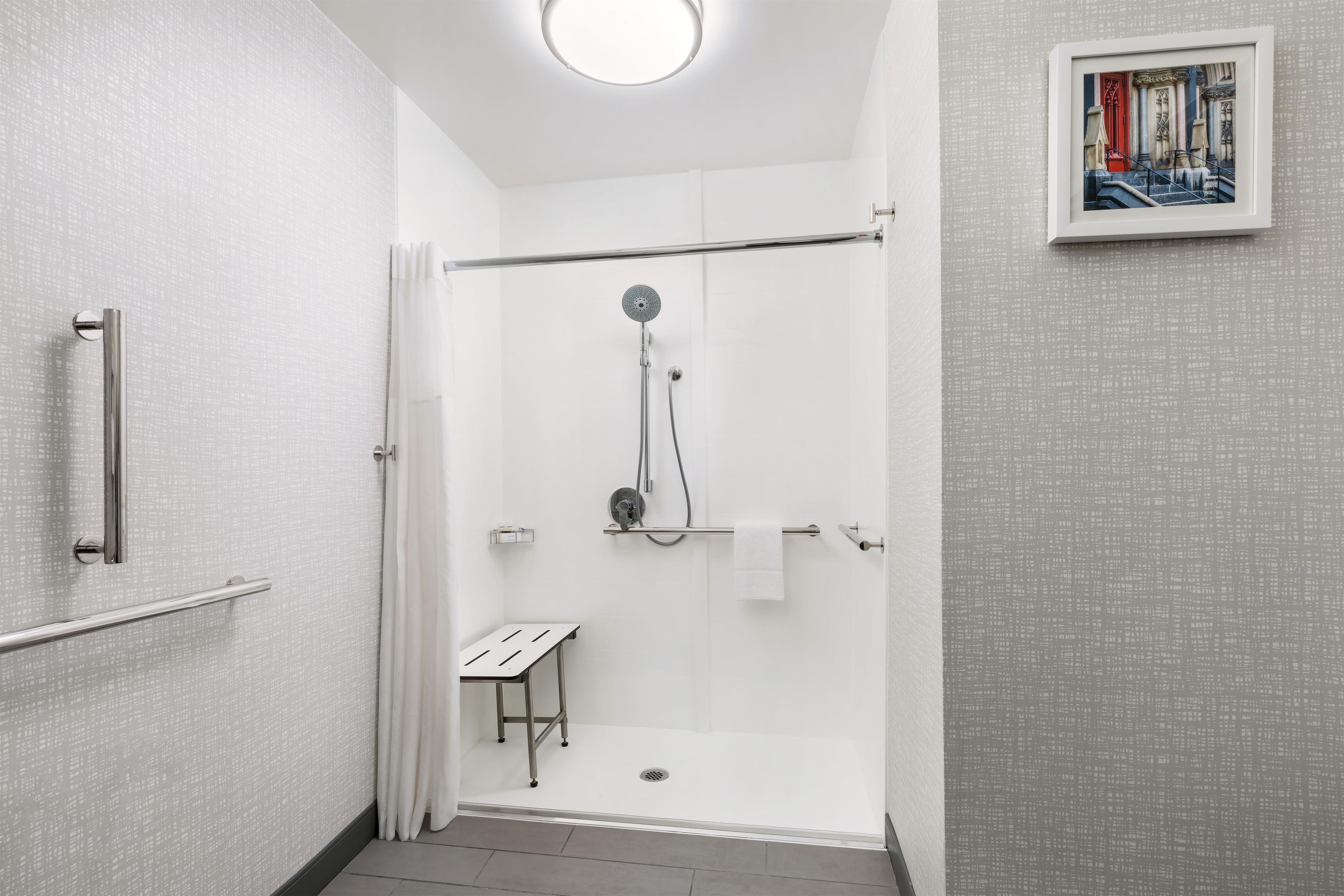 Een moderne badkamer met een inloopdouche, een handdoekhouder en een klein tafeltje.