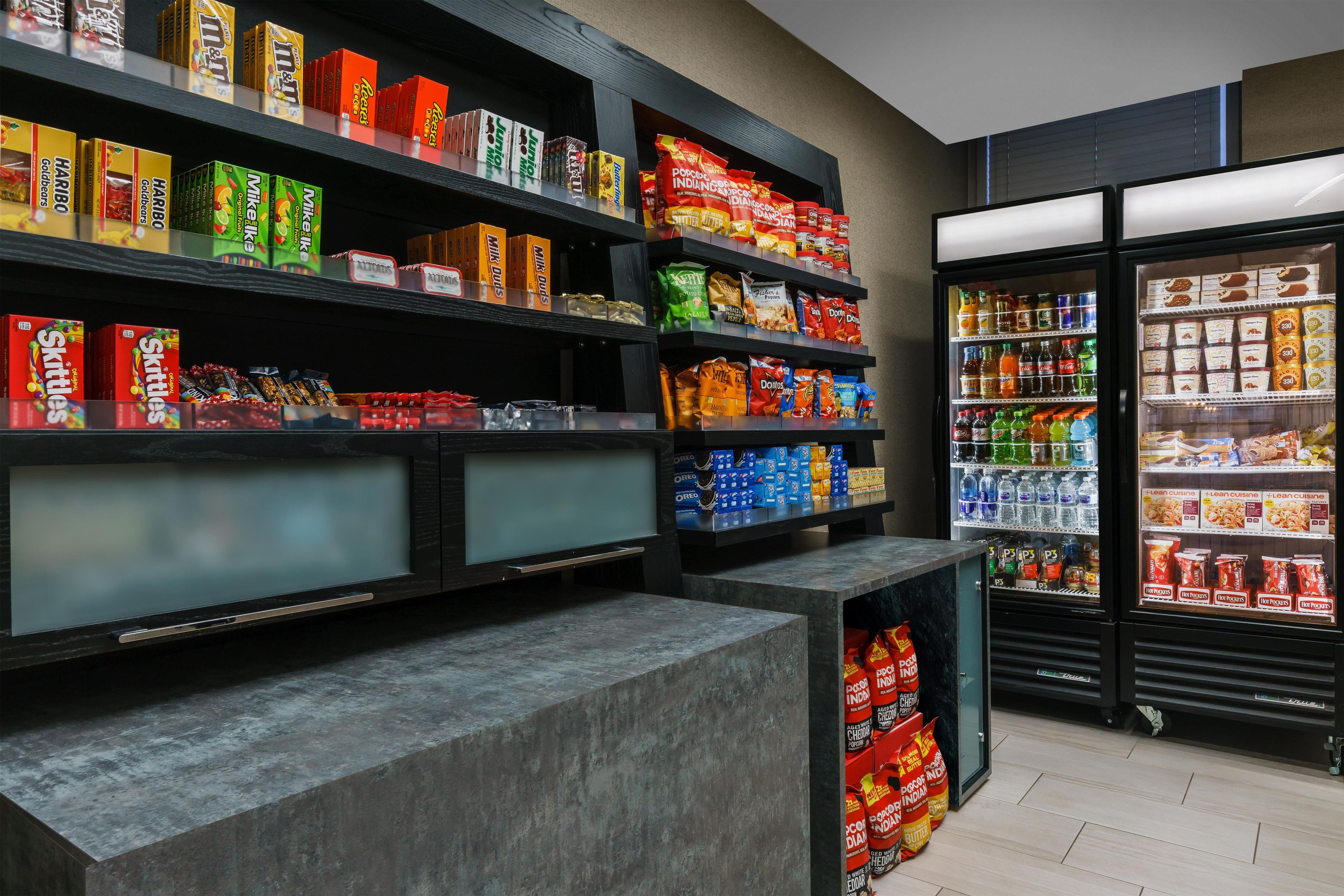 A grocery store interior with shelves stocked with various snacks and beverages.