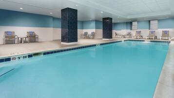 Una piscina interior con borde de azulejos, sillas de descanso y una decoración azul y blanca.