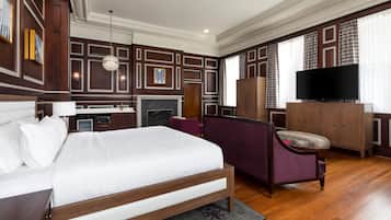 A hotel room with a large bed, a television, a desk, and a wardrobe.