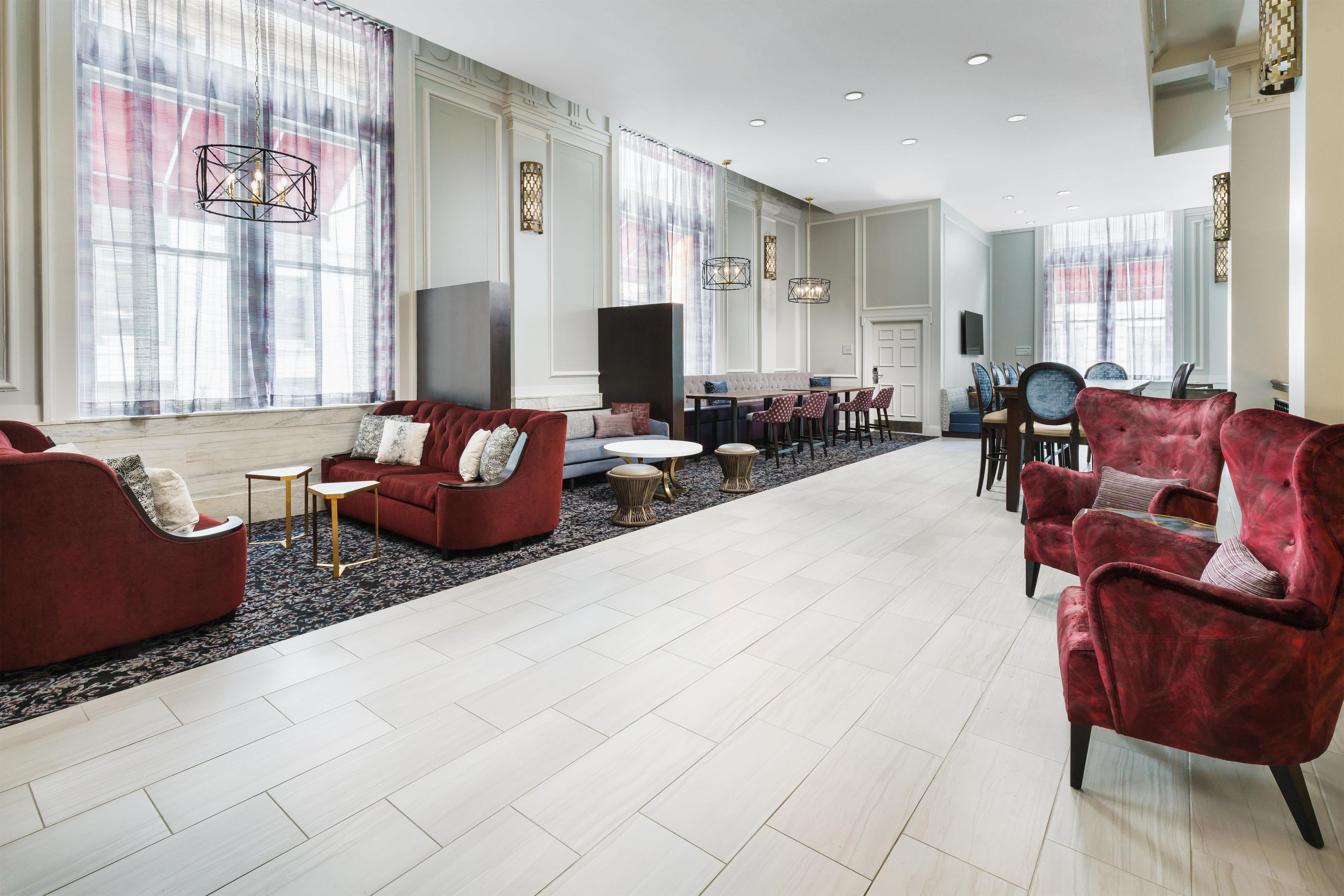 Un amplio vestíbulo de hotel con una zona de estar, una mesa de comedor y una televisión.