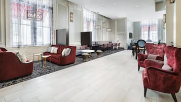 A spacious hotel lobby with a seating area, a dining table, and a television.