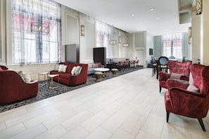 A spacious hotel lobby with a seating area, a dining table, and a television. - Hampton Inn & Suites Baltimore Inner Harbor (Baltimore)
