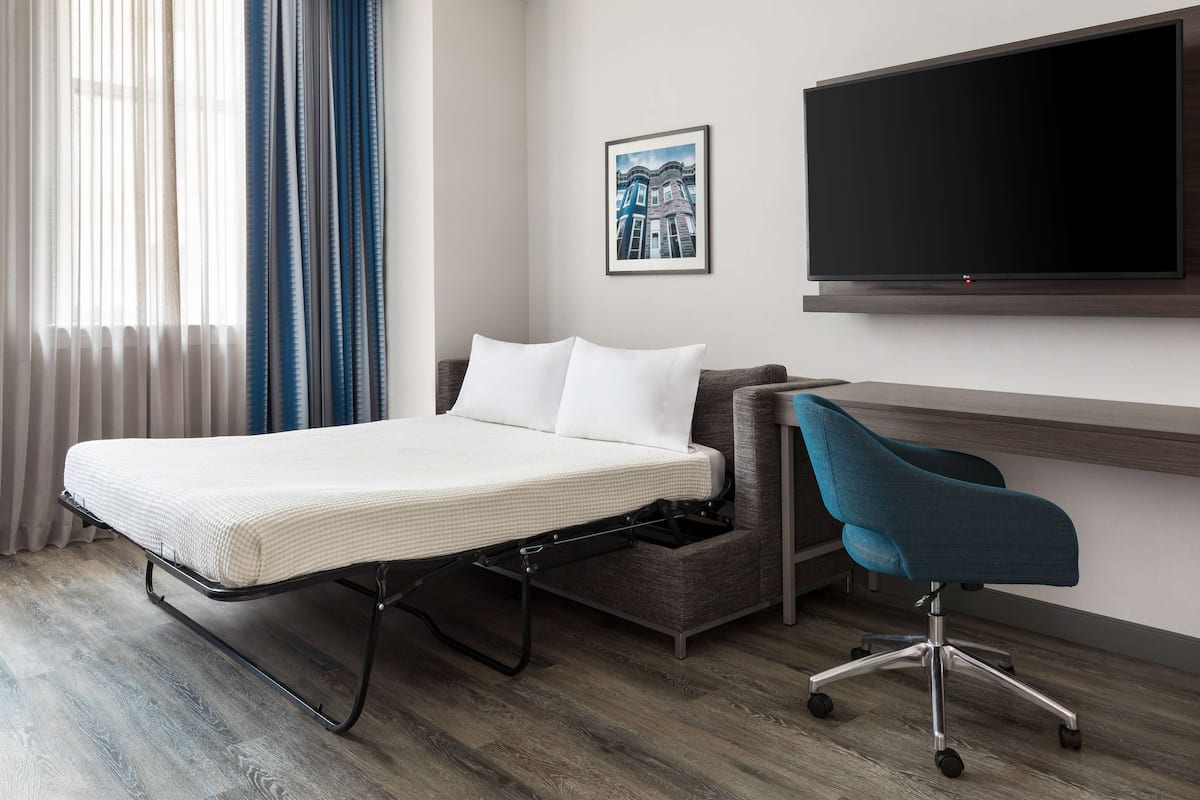 Ein Hotelzimmer mit Bett, Schreibtisch und Stuhl.