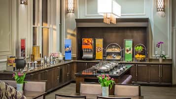 A modern kitchen with a central island, equipped with various appliances and a buffet setup.