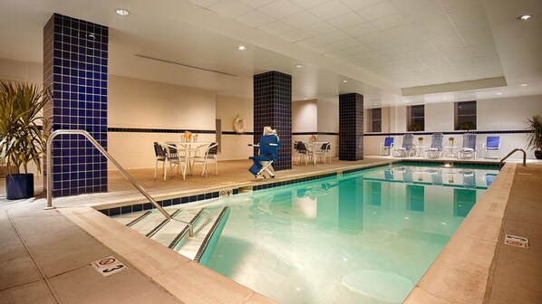 A hotel swimming pool with a lifeguard chair, lounge chairs, and a table with chairs. - Hampton Inn & Suites Baltimore Inner Harbor (Baltimore)