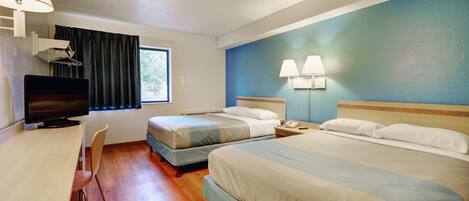 A hotel room with two beds, a desk with a chair, a television, and a window with curtains.