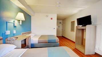 Una habitación de hotel con dos camas, un escritorio con teléfono, un televisor sobre un mueble bajo y un armario.