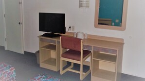 Ein Zimmer mit einem Holztisch, einem Fernseher, einem Spiegel und einer Tür.