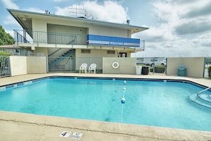 A swimming pool with a lifebuoy, a 'Welcome' sign, and a staircase leading to an upper level. - Skyline Inn (Conway)