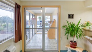 Un hall d’hôtel doté d’une porte coulissante en verre donnant sur le comptoir d’accueil, d’une plante en pot posée sur une petite table et d’une plaque commémorative au mur.