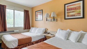 Une chambre d’hôtel avec deux lits, une fenêtre avec des rideaux, une lampe fixée au mur et un tableau encadré.