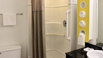 A bathroom with a shower, toilet, and sink. There are towels hanging on a rack and a mirror with a yellow accent wall.