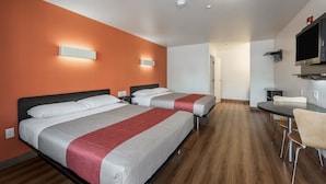 Una habitación de hotel con dos camas, un escritorio, una silla y un televisor.